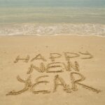 Happy new year written in the sand on a beach