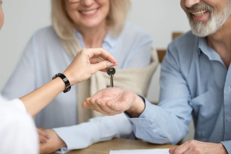 Realtor giving senior couple key to new house at meeting