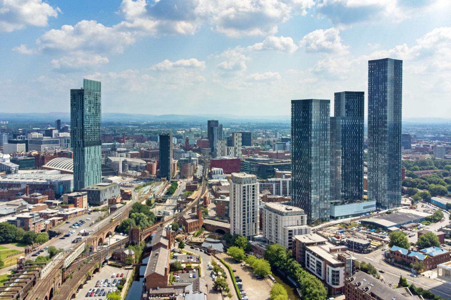 An aerial view of the Manchester skyline from Deansgate, showing multiple high-rise properties